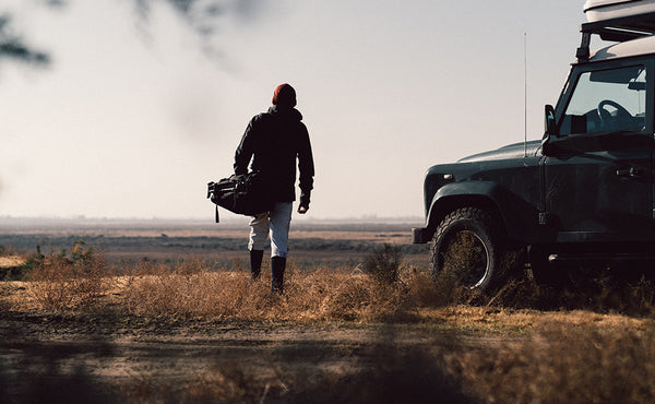 A person carrying the Road Buddy Duffel 60 via the padded carry handle.